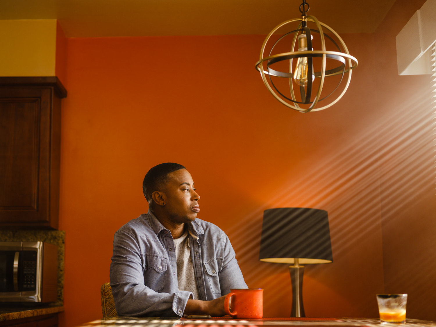 Man sitting looking out window rays of light.