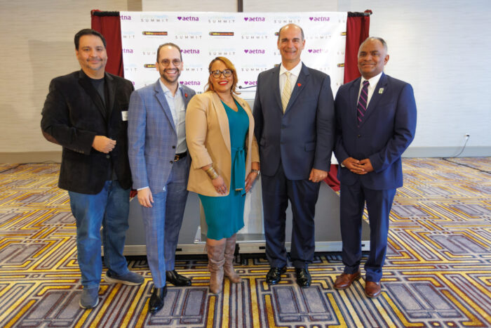 Group of people standing in front of a backdrop with logos.